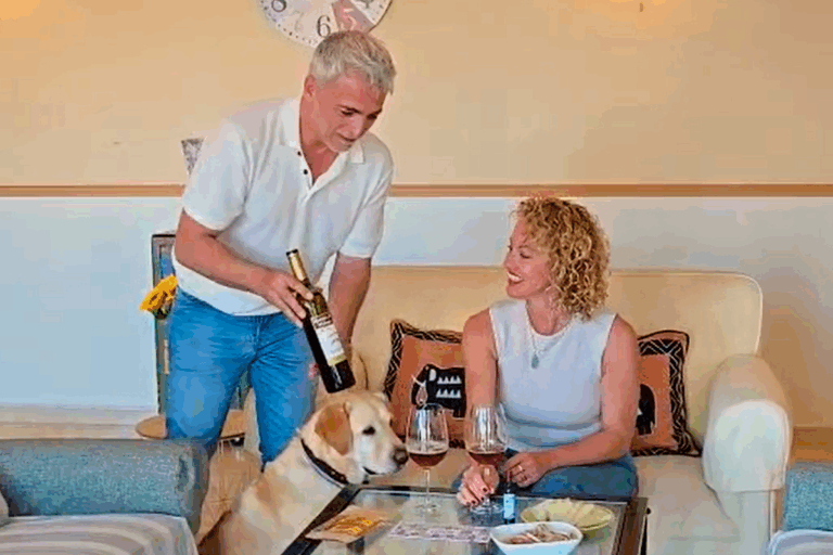 Fotografía de un hombre mostrando un vino y una mujer sonriendo.